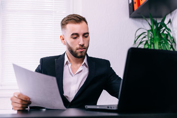 Confident businessman types sitting at desk with laptop, focused