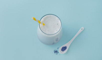 a Cup of  matcha tea  and a yellow paper tube on a blue background. Top view and copy space