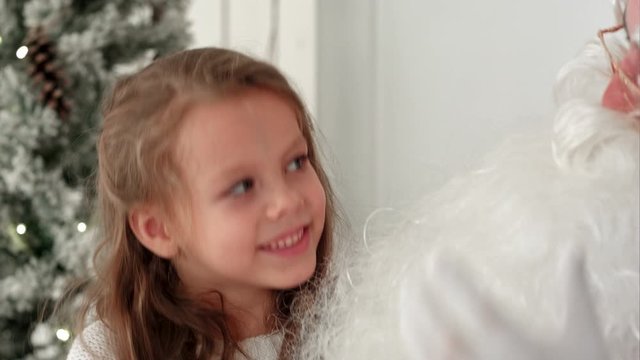 Cute little girl singing Christmas song together with Santa Claus