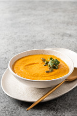 Pumpkin soup with cream on grey background. Close up. Copy space.