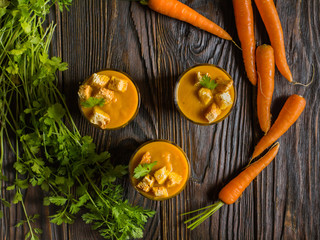 Carrot soup. Fresh carrot ginger soup with ingredients on dark wooden background