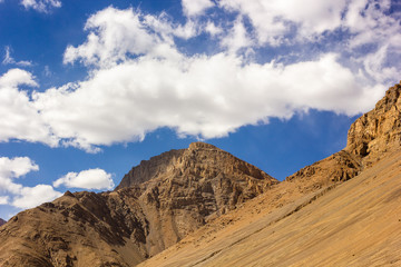 The craggy mountains against a blue sky and white clouds in the village of Kaza in the Spiti Valley in Himachal Pradesh, India.