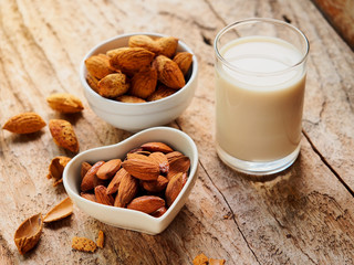 Raw almonds nut and almond milk glass on a rustic wooden table for healthy eating or vegetarian...