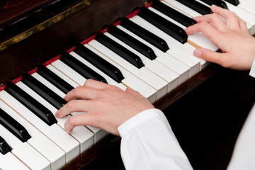 hands of a schoolgirl in a white shirt on the piano keys. selective focus