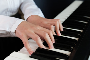 Obraz premium a schoolgirl in a white shirt plays the keys of a synthesizer. selective focus