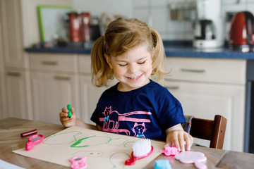 little toddler girl painting with felt pens during pandemic coronavirus quarantine disease. Happy creative child, homeschooling and home daycare with parents