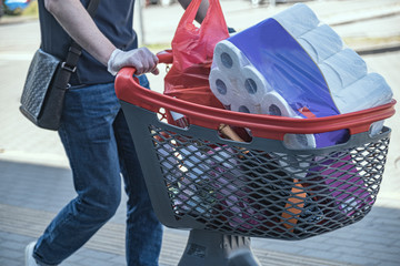the buyer rolls the shopping cart from the store to the car. A lot of shopping in the basket.
