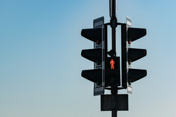 Close-up of a traffic light with a red signal at a crosswalk against a blue sky