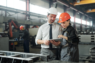 Asian metalworking specialist discussing technical sketch with engineer while they using...