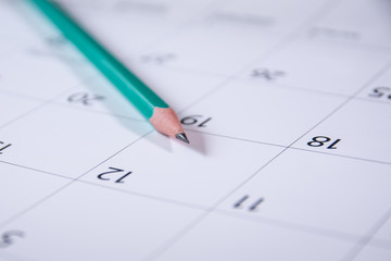 a green slate pencil lies on an opened blank calendar. Work planning.
