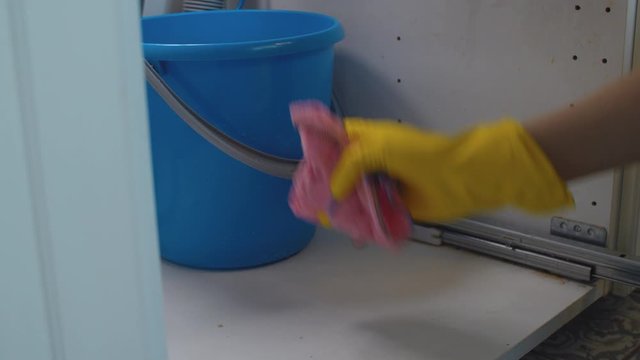 Close up woman's hands wiping the water with a rag. Water flowing from a syphon under the kitchen sink. Plumbing in need of repair. Housekeeping