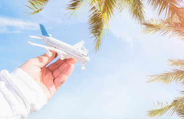 Man hand holding airplane model over sea background dreams of journey in vacation.