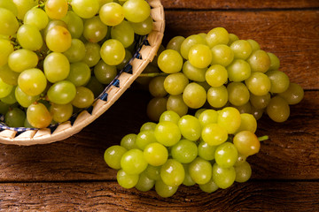 Bunch of green grapes in the basket, fruits of autumn, a symbol of abundance on rustic wood background with copy space, top view, close-up