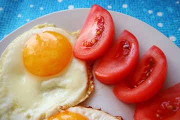 Breakfast food fried eggs with tomatoes on a plate