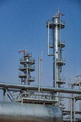 Grey fractional distillation columns, heat exchanger and pipes. Oil refinery plant. CNPC company. Against blue sky