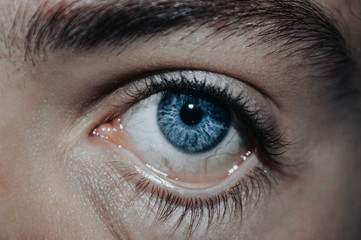 Close up of Finger opening the Eye. Blue Eye with Veins. Ophtalmology concept. Eye Treatment
