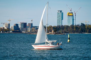 A small sailboat sailing across urban cityscape on a sunny spring day.