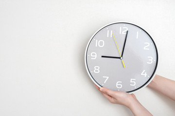 Woman hand changing time on white clock. Time change concept and punctuality.