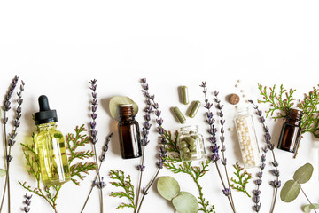 Fototapeta Homeopathy eco alternative medicine concept - classical homeopathy pills, thuja, eucalyptus, lavender essential and aroma oil and healing herbs and on white background. Flatlay. Top view. Copyspace obraz