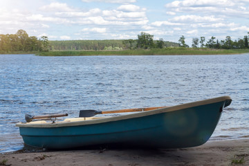 Naklejka na ściany i meble Lonely green rowing boat on lake shore for wild journey