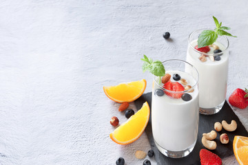 Two fermented drink kefir glasses and nuts, berries, citrus fruits with immune boosting properties white background with copy space.