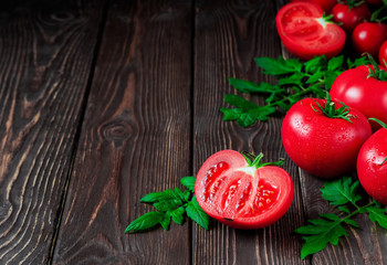 Slice of tomato and ripe red tomatoes close-up on a dark rustic background. Ripe vegetables from the market, ingredients for the preparation of salads or dishes. Copy space
