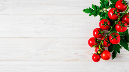 Fresh cherry tomatoes on a branch with leaves in the upper right corner on a white vintage wooden background. Ripe tomatoes in droplets of water. Copy space for text, flat lay. - Powered by Adobe