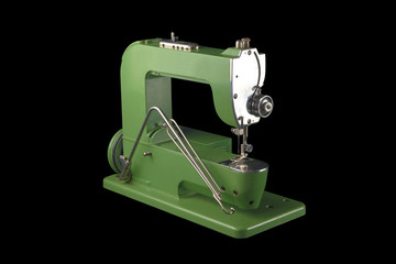side view of an old vintage green sewing machine on black background