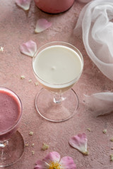 A glass of goat kefir on a pink background