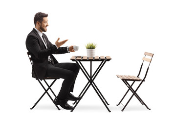 Young man in suit and tie sitting in a cafe and drinking coffee