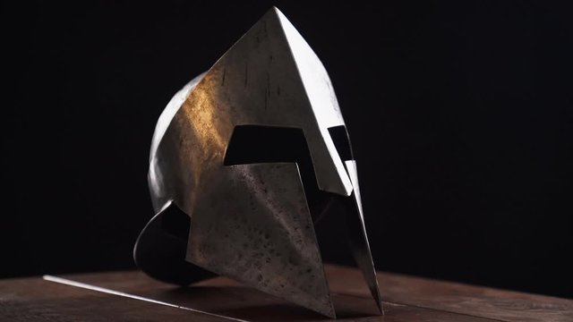 Ancient iron spartan helmet on table.