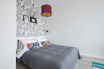 A white wooden bed in a bright Scandinavian style bedroom with bright linens and vintage lamps