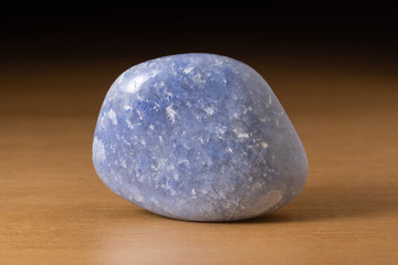 Polished dumortierite quartz gemstone from Portugal over a wooden table
