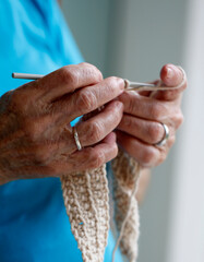 M&atilde;os de senhora idosa tricotando
