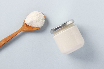 Vegan organic paste of coconut in glass jar and coconut flour in spoon on light blue background, urbech, Healthy food product, Top view