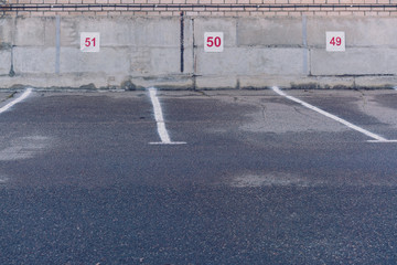 empty spacious parking area with place numbers on grey wall in spring morning