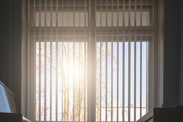 sun shines through gymnasium window with white jalousie against clear sky