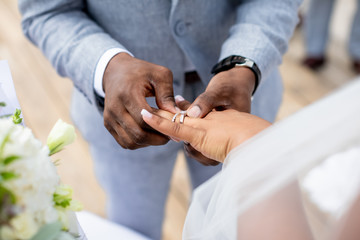 Bride and groom exchanging wedding rings close up during symbolic nautical decor destination...