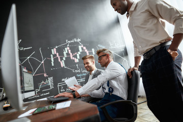 Open. Honest. Hardworking. Three stock traders are happy with the results while looking at graphs,...