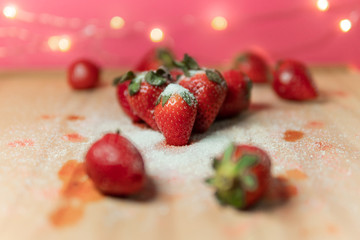Fresh red strawberries with sugar on top on wood table. Vegan food ingredients for natural dessert. Healthy fruit summer vibes.