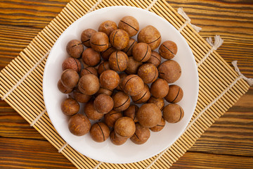 delicious macadamia nuts on  plate on  wooden background
