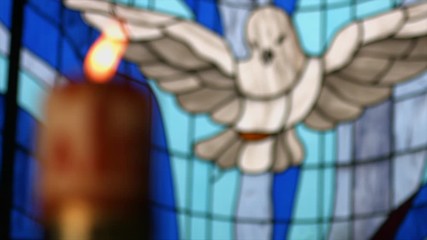 stained glass with figure of the holy spirit and candle or paschal candle