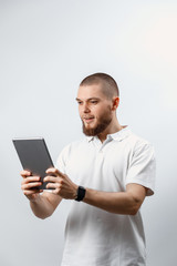 Portrait of a handsome bearded man in a white T-shirt talking video calling tablet. isolated, emotions