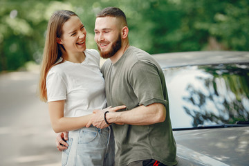 Obraz premium Couple in a forest. Man in a green t-shirt. Pair near car