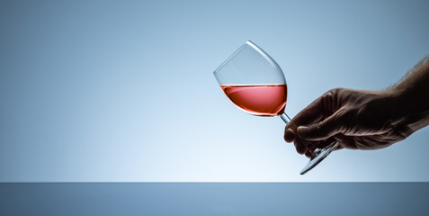 Hand holding a glass of red rose wine