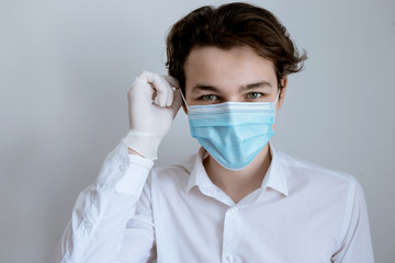 man in a medical mask with medical gloves on a white background, face of a man, a doctor in a blue medical mask on a white background