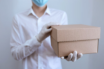 courier in white gloves holds a parcel in a craft box