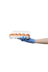eggs held in hand isolated on white background. man wearing blue gloves holding plastic package in palm. delivery during quarantine of coronavirus pandemic COVID-19. food supplies, donation, volunteer