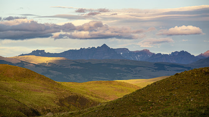 valle colorido por el atardecer/amanecer con vista a grandes montañas y nubes 