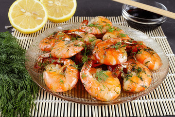 fried king prawns in a plate on a bamboo mat, lemon, dill, close-up